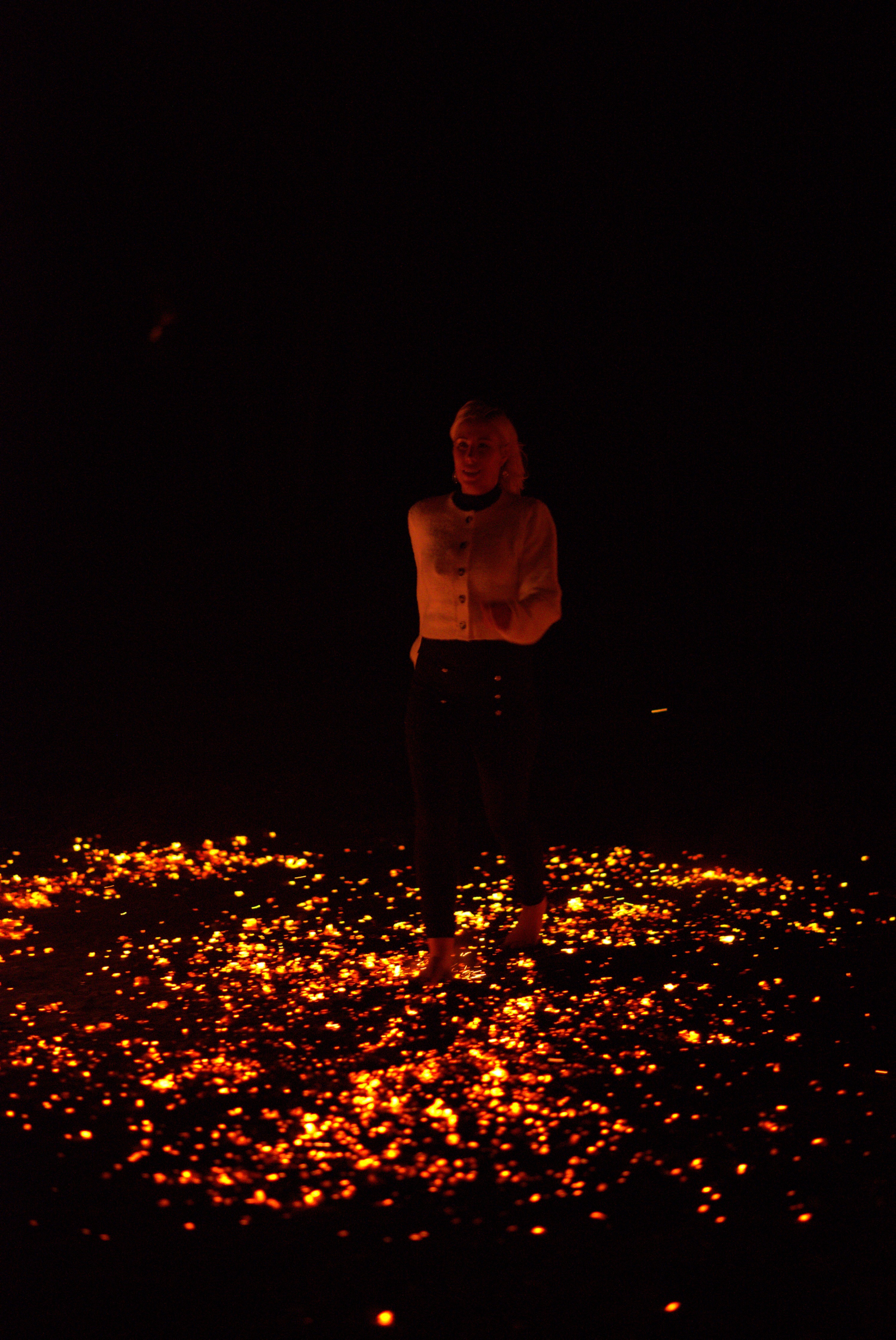 A participant crossing a wide field of glowing embers at night