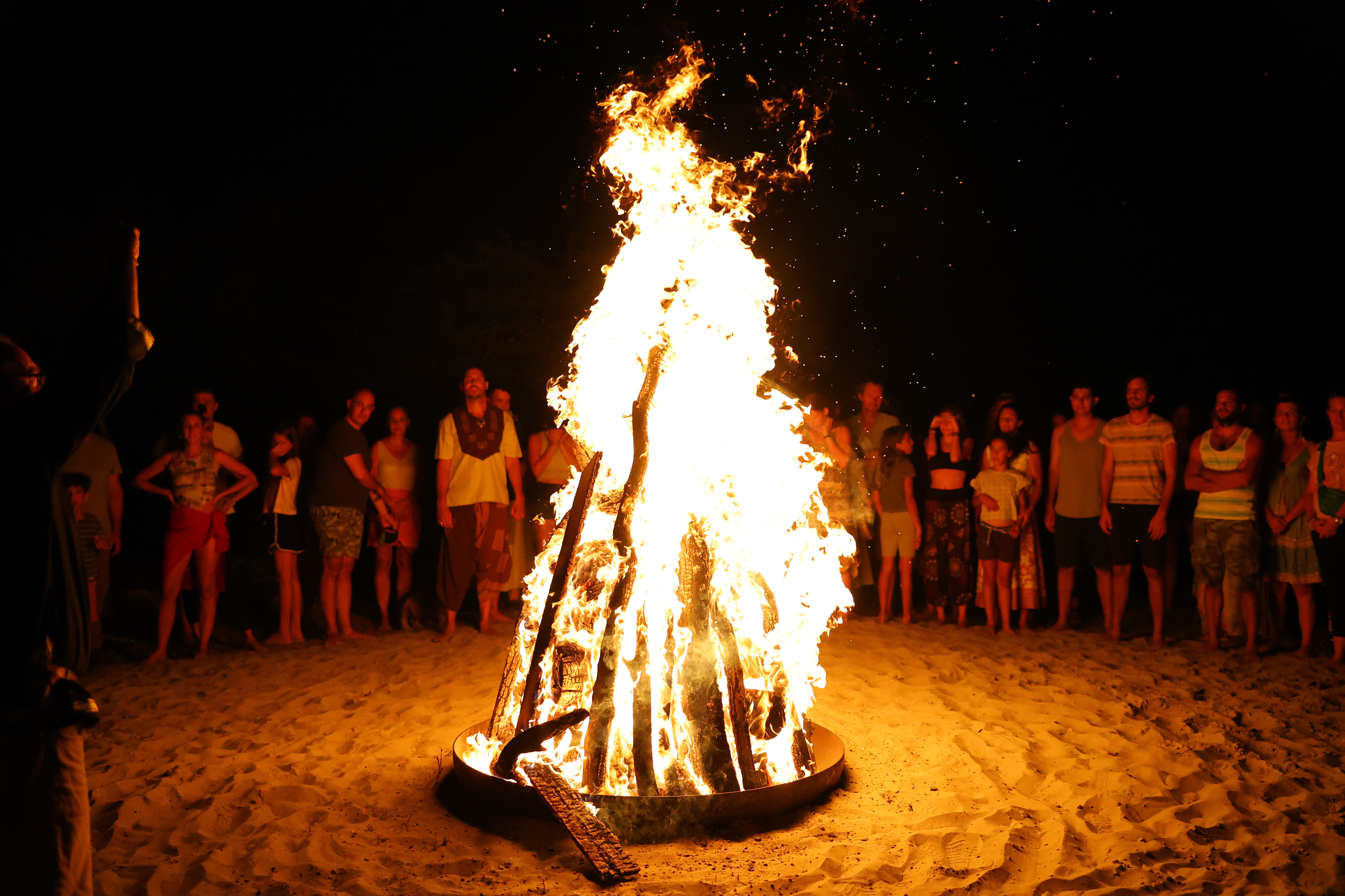 A community gathered in a circle around a fire at night