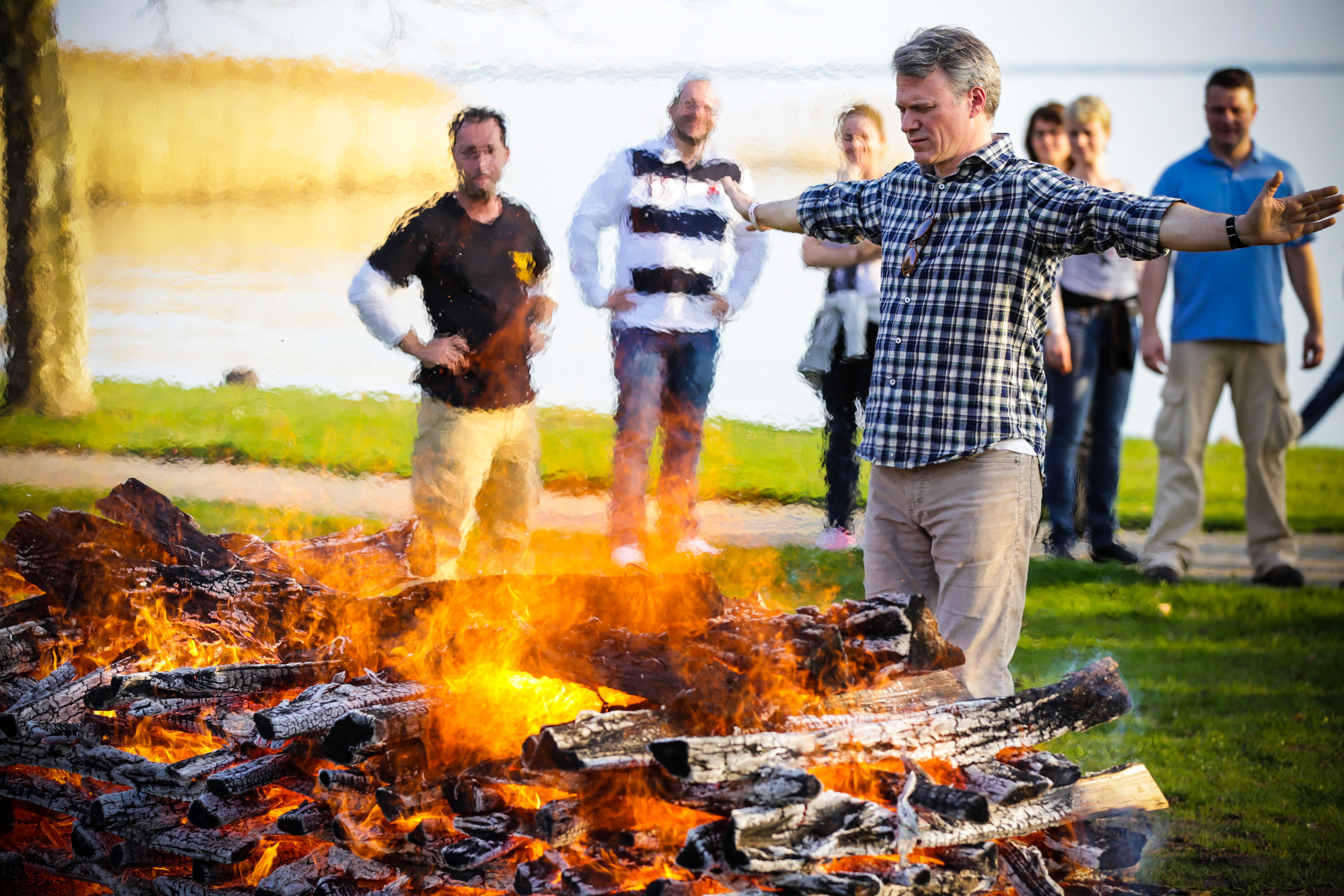 A participant opening his arms to the heat of the fire with colleagues behind him