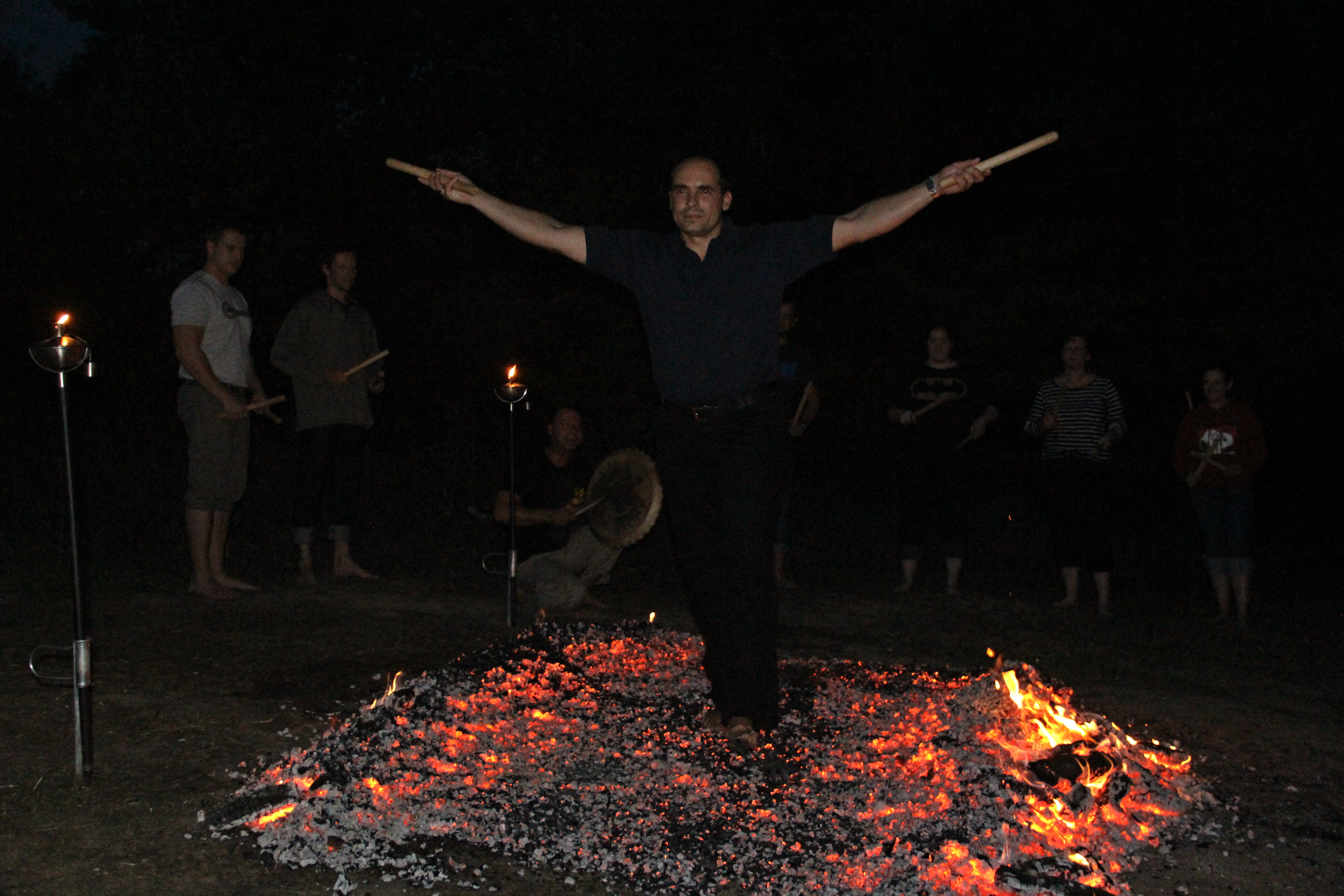 A participant crossing a classic firewalk with outstretched arms