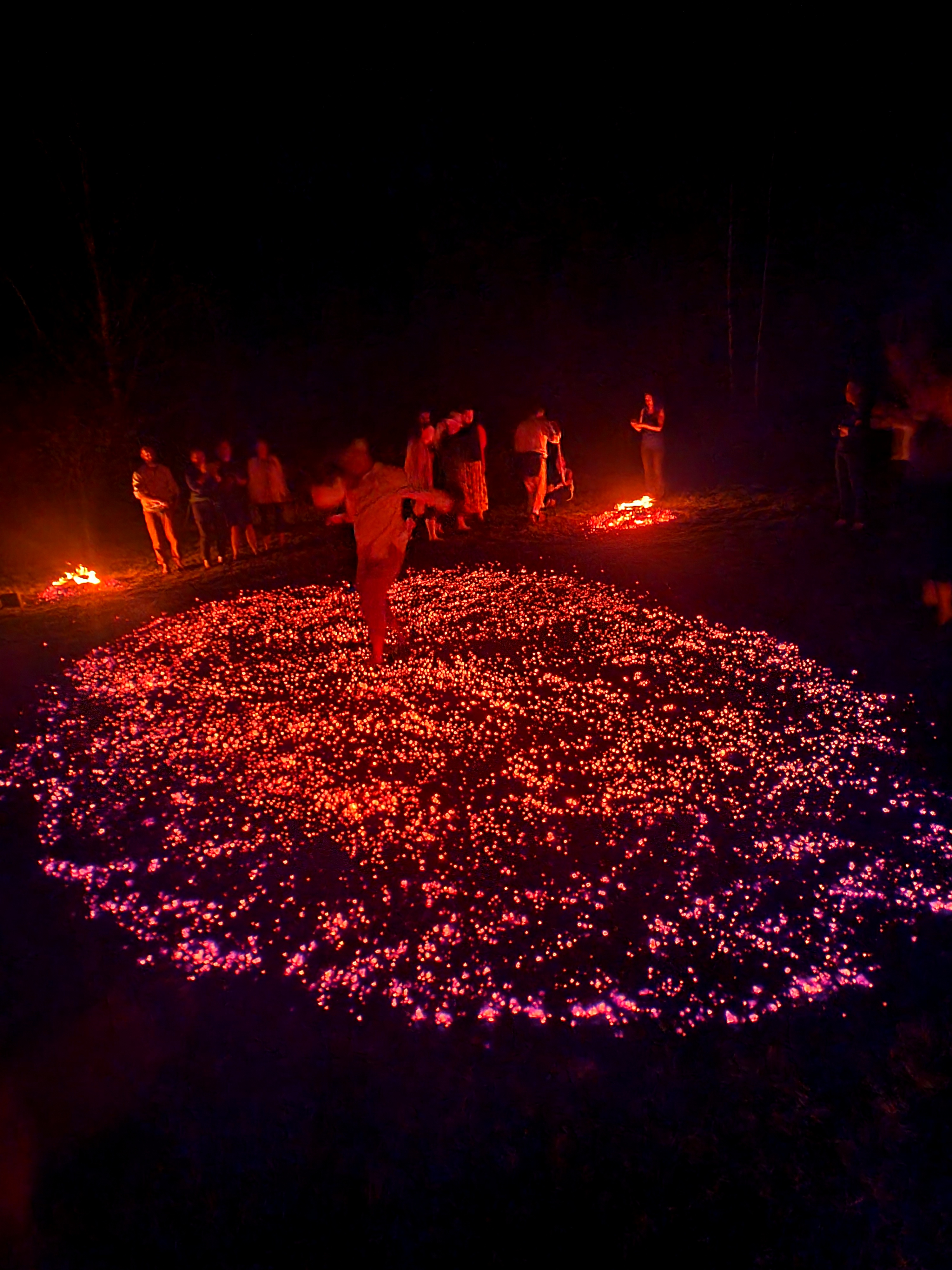 A participant walking across a large circular field of glowing embers
