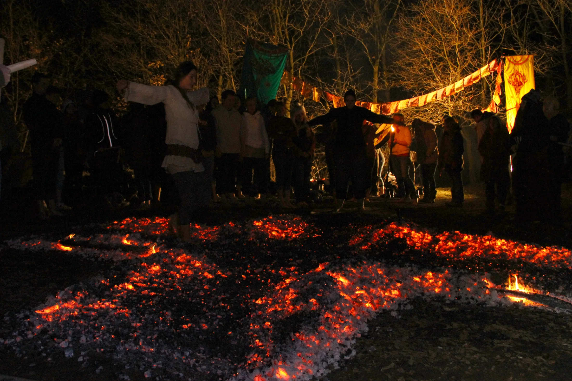 A community gathered with open arms around intersecting ember paths