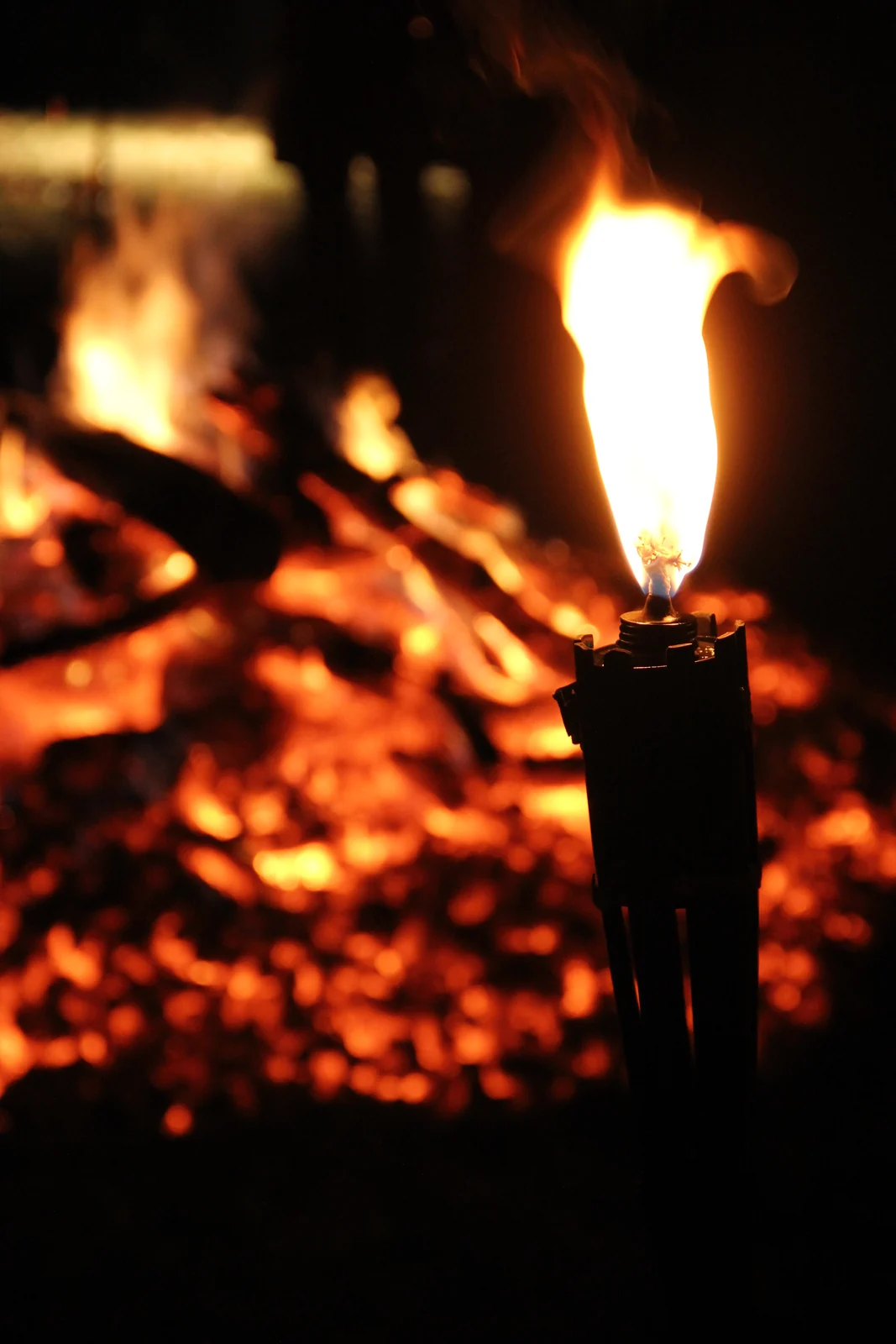 A single flame burning beside glowing embers