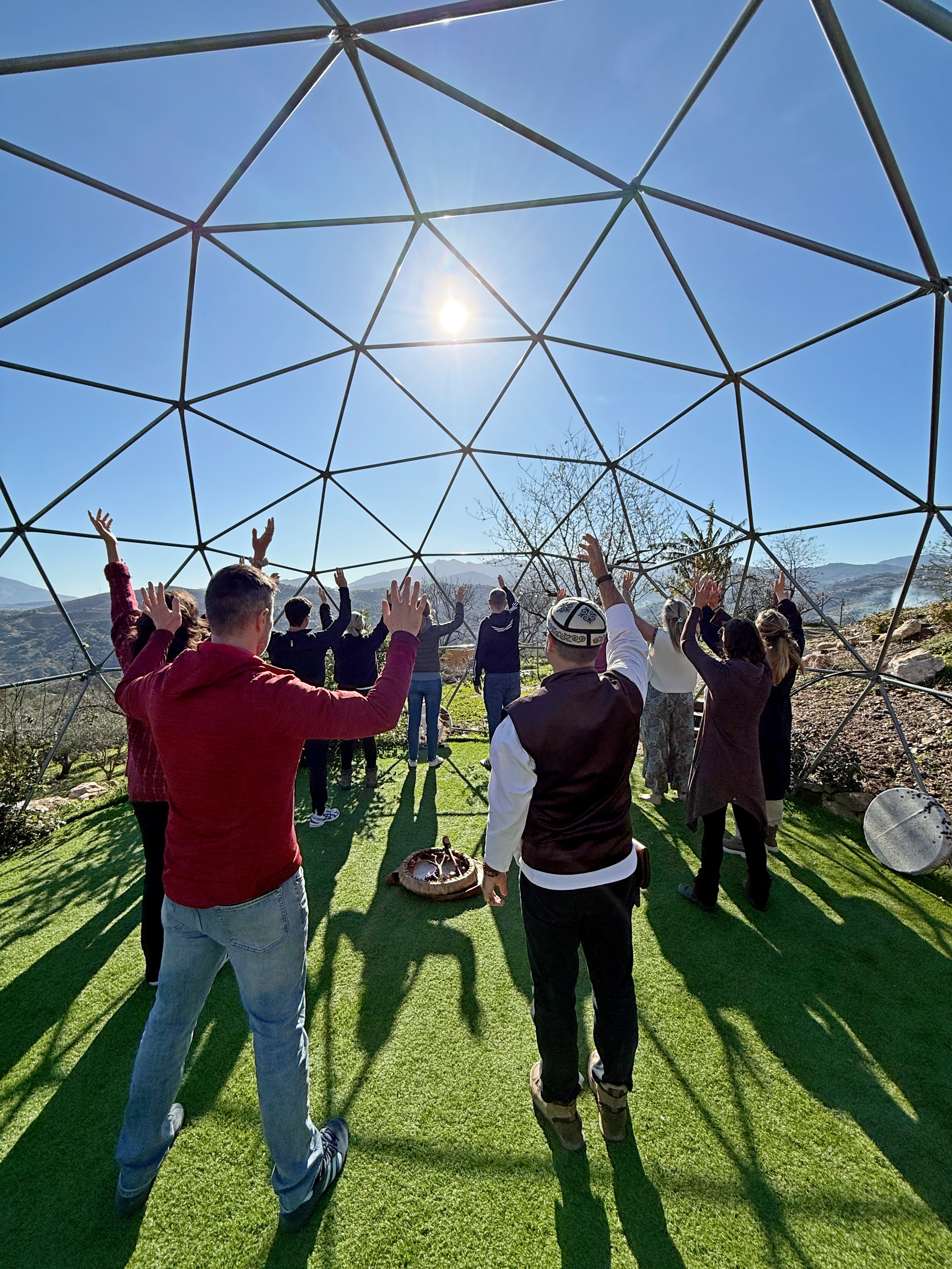 Participants raising their hands during a group practice beneath a geometric dome