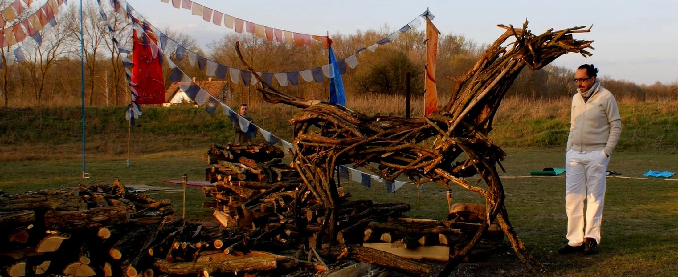 A participant standing beside a carefully constructed fire sculpture before the programme