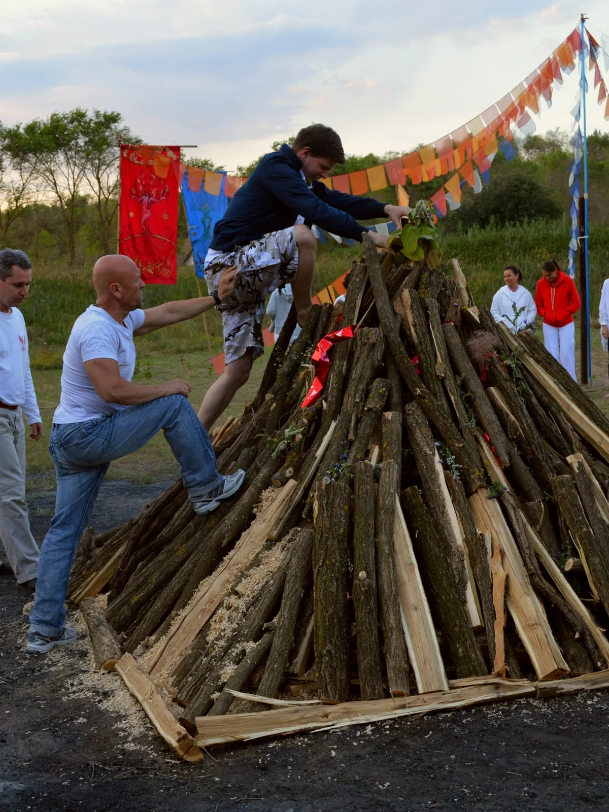A participant climbing a pyramid-shaped pyre during group preparation