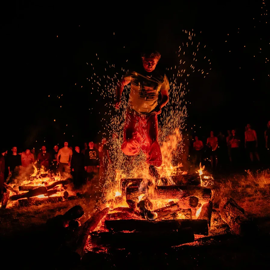A participant taking a decisive step above a ceremonial fire