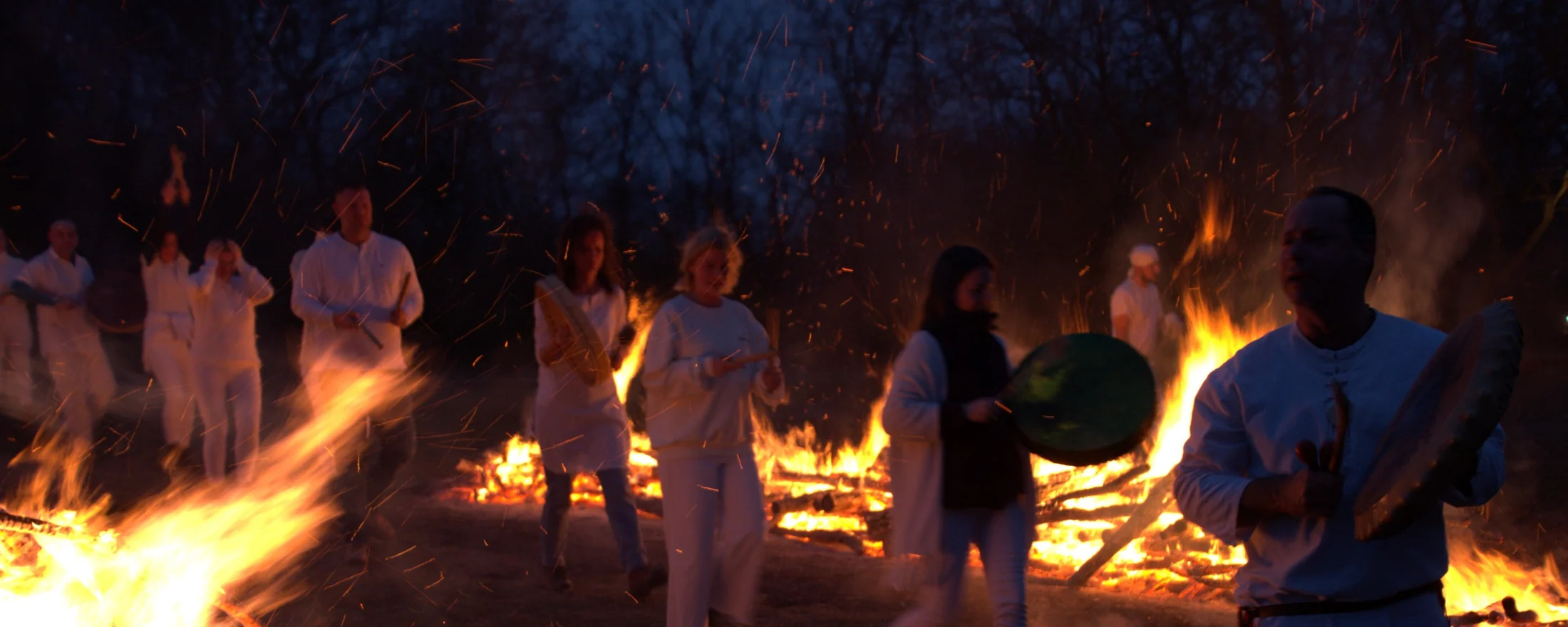 A ceremonial firewalking gathering surrounded by flames and flying sparks