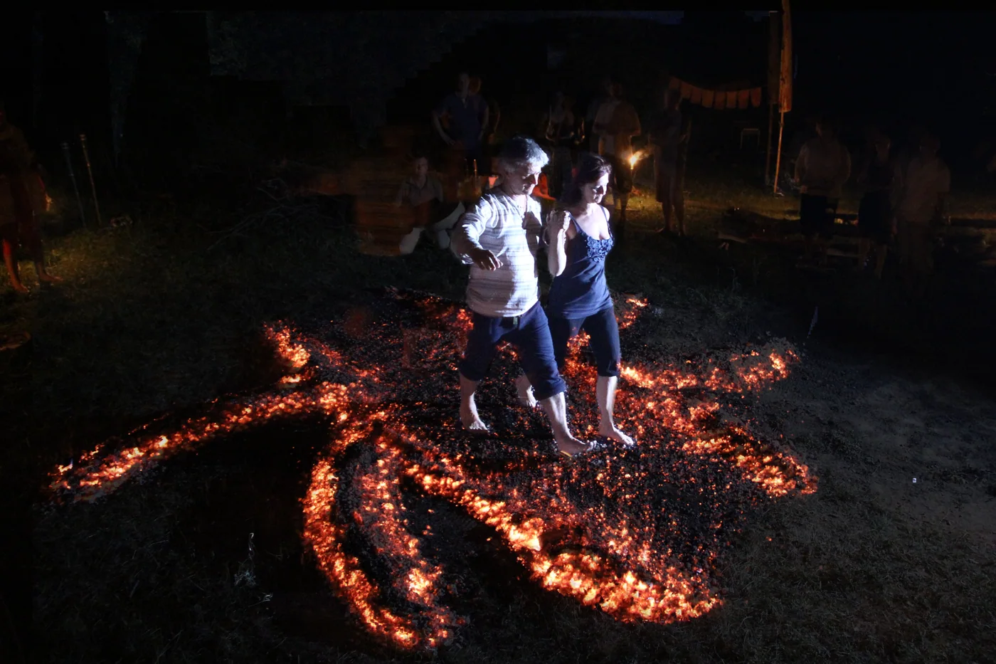 Two participants crossing a glowing ember pattern together