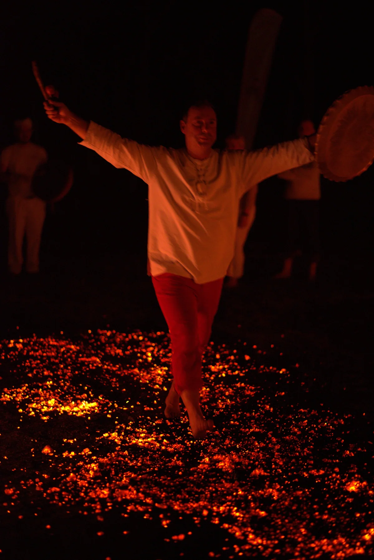 A firewalker crossing the glowing embers with arms outstretched